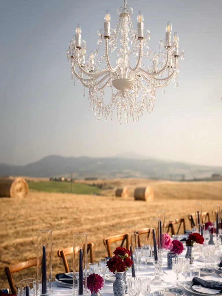 A crystal chandelier above a dinner table in the hay field